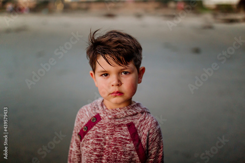 Serious clean-cut boy wearing sweatshirt at the beach