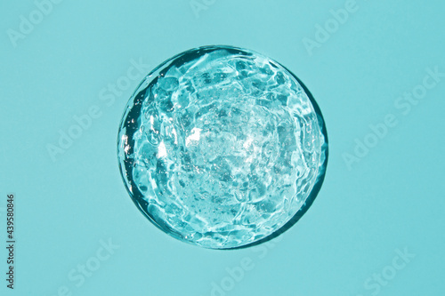 Close-up transparent cosmetic gel in glass isolated on blue background