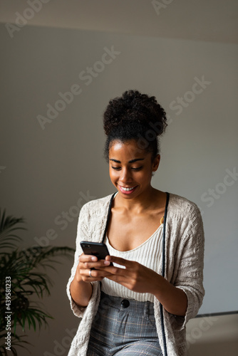 Black woman browsing cellphone in cozy room photo