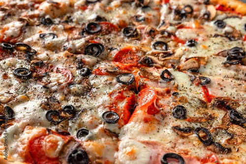 traditional Italian pizza background with cheese, olives, tomato, onion, pepperoni sausage close-up