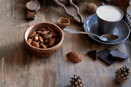 cup of coffee, different kinds of nuts, walnut, hazelnuts, almonds on old wooden table boards, edible seed kernels, food concept, confectionery ingredient