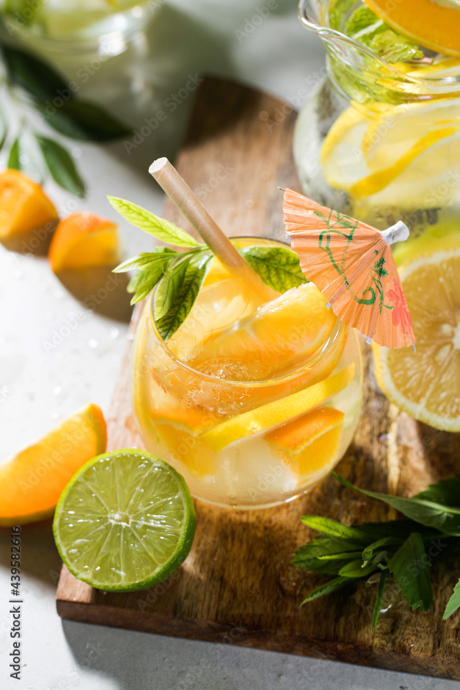 Fototapeta premium Refreshing lemonade with lemon and mint in a jug and glass on a wooden board. Summer drinks. Copy space.
