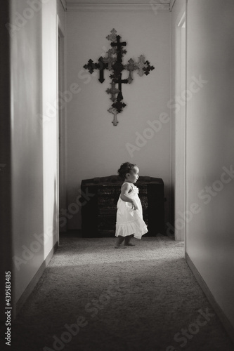 Girl in white dress in hall with crucifix