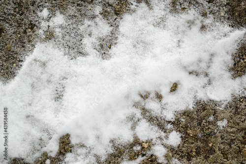 A patch of white snow on a granite surface. Winter background concept.