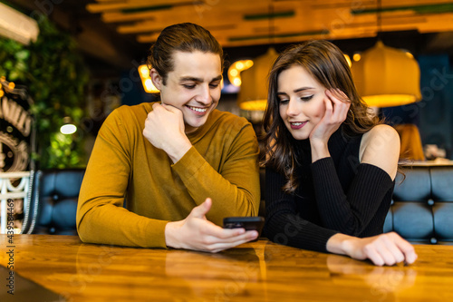 Young smiling couple in gorgeous restaurant looking at phone. © F8  \ Suport Ukraine