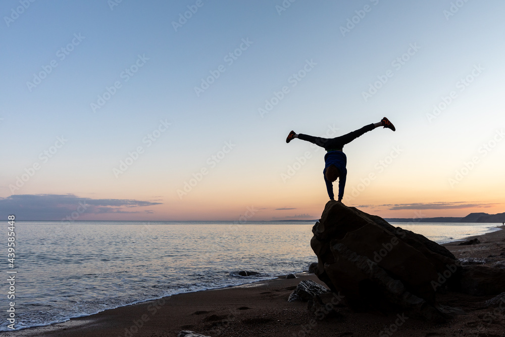 Boy performing a handstand on a rock Boy performing a handstand on a rock