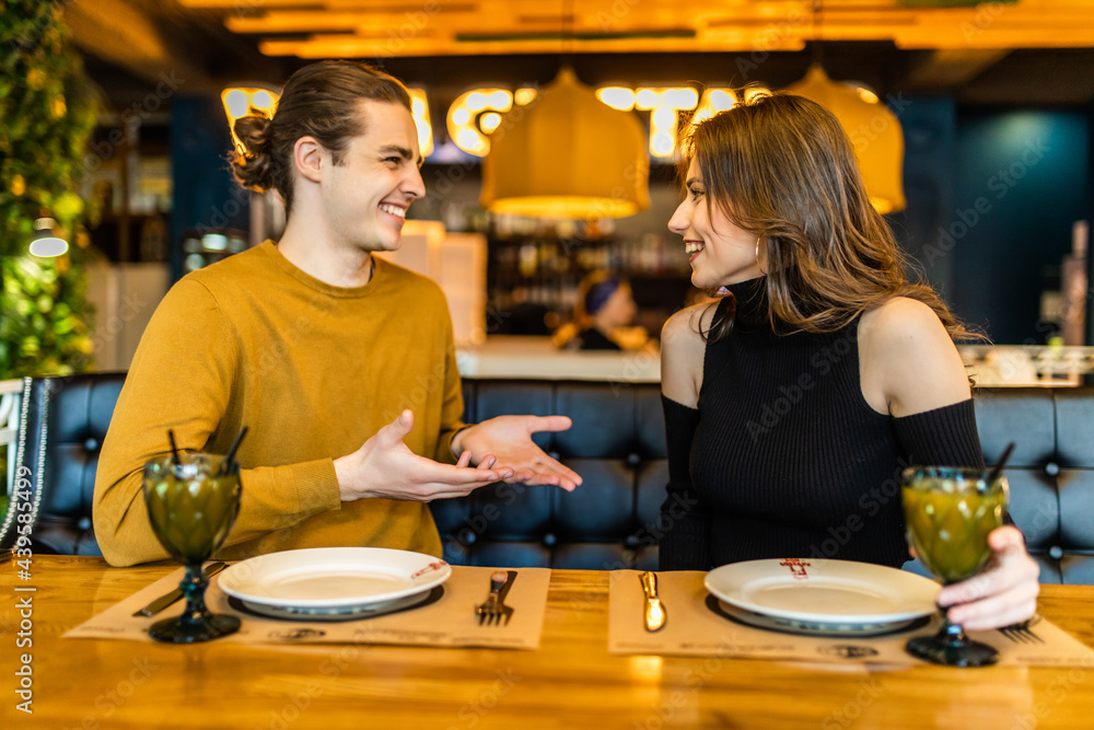 Happy young couple in love having a nice date in a bar or restaurant telling some stories about themself Happy young couple in love having a nice date in a bar or restaurant telling some stories about themself