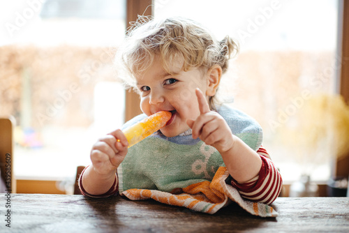 Toddler girl eating an ice cold popsicle