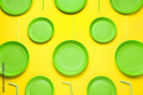 Plastic dishware on yellow background, flat lay