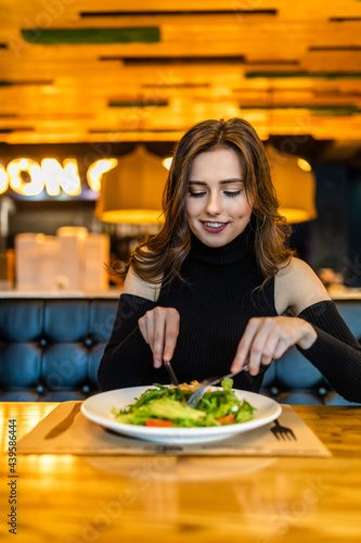 Happy young woman eating lunch in restaurant