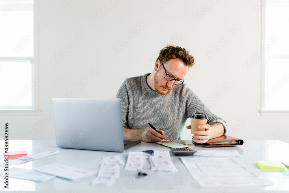Red Headed Man Enjoys Coffee While Calculating His Startup Company's Expenses Red Headed Man Enjoys Coffee While Calculating His Startup Company's Expenses