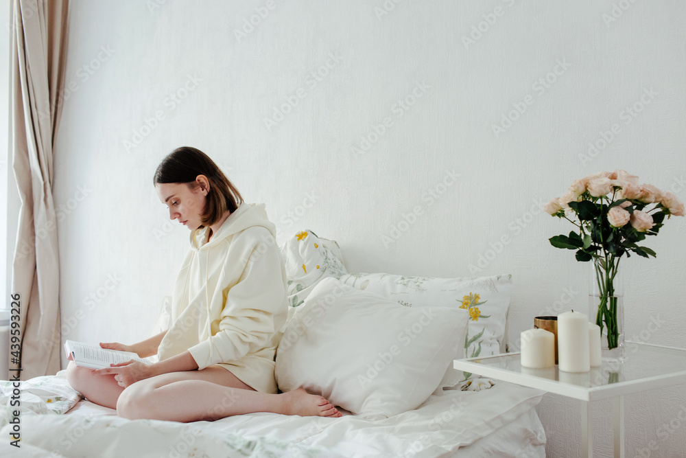 Tranquil woman sitting on bed and reading book Tranquil woman sitting on bed and reading book