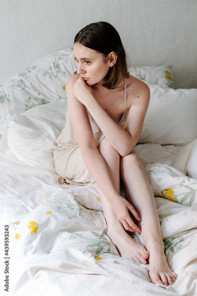 Delicate woman sitting on bed in morning Delicate woman sitting on bed in morning