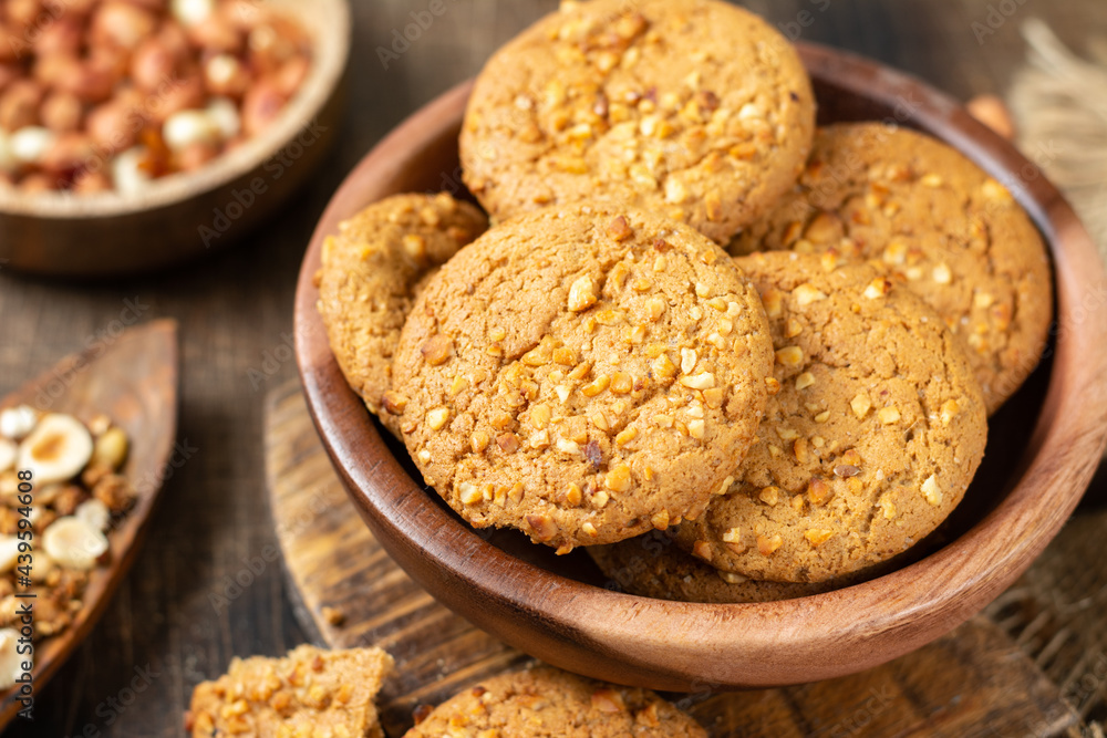 Healthy homemade oatmeal cookies with peanuts in a wooden bowl on a brown kitchen table closeup Healthy homemade oatmeal cookies with peanuts in a wooden bowl on a brown kitchen table closeup