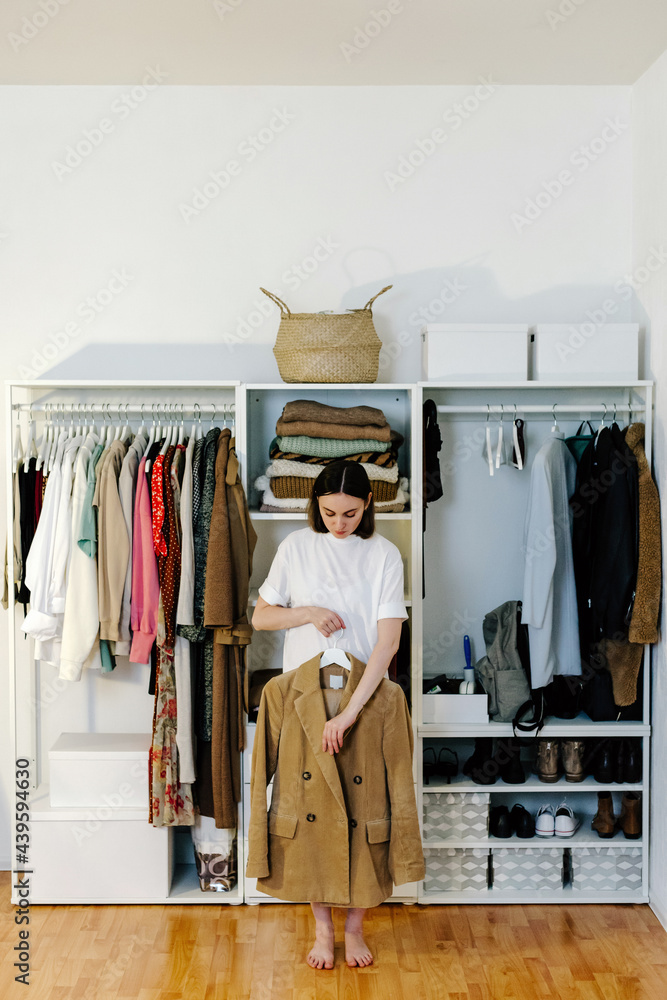 Woman standing with stylish jacket near wardrobe Woman standing with stylish jacket near wardrobe