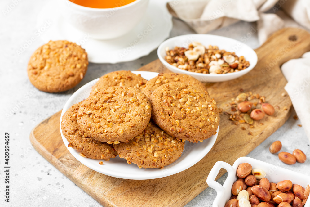 Healthy homemade oatmeal cookies with peanuts in a white plate on a light gray kitchen table closeup Healthy homemade oatmeal cookies with peanuts in a white plate on a light gray kitchen table closeup