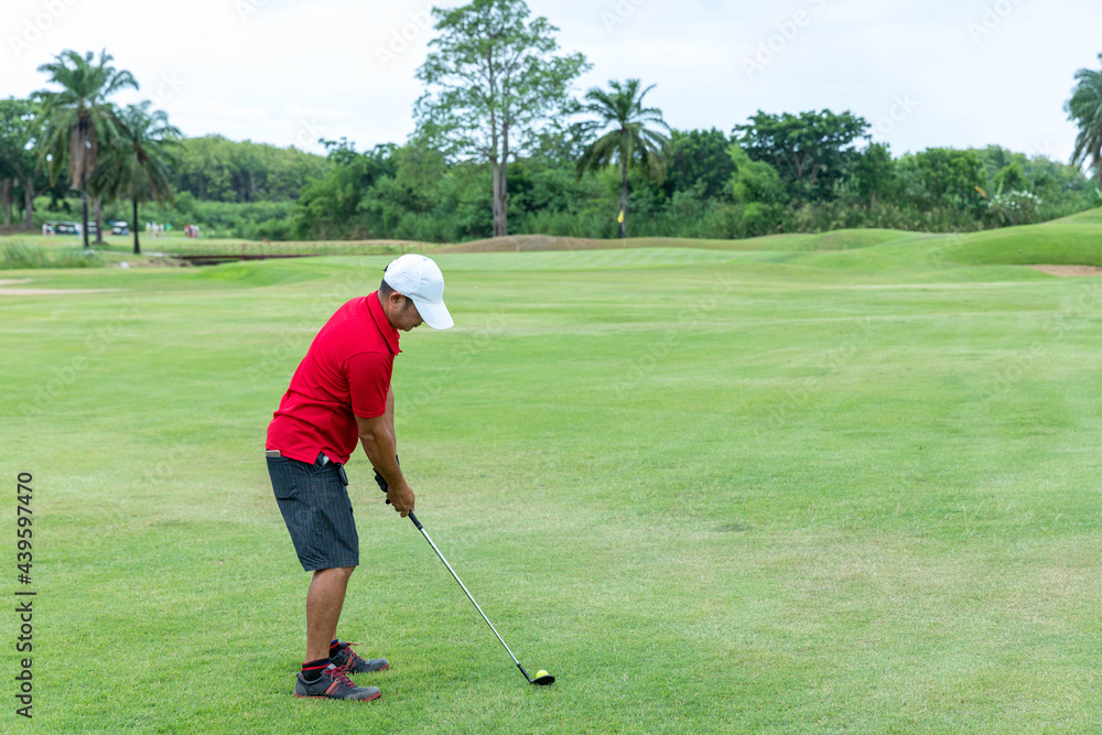 Fototapeta premium Male athlete hitting a golf ball into a hole