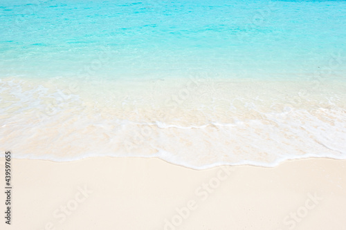 Clean fine sand beach, white foam and blue-green water in Maldives