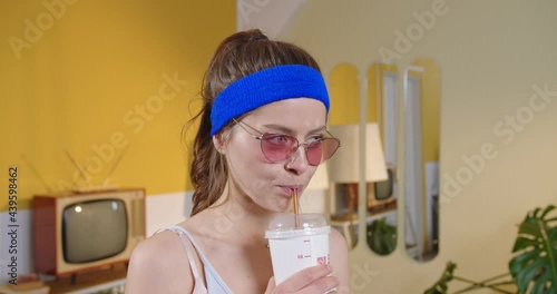 Portrait view of the young woman wearing glasses looking away and drinking unhealthy cola during the training. Weight loss, fitness, will power, choice between healthy and unhealthy lifestyle concept photo