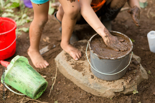 Children play with bucket of mud photo