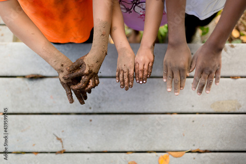 Multiracial siblings hold out muddy hands photo