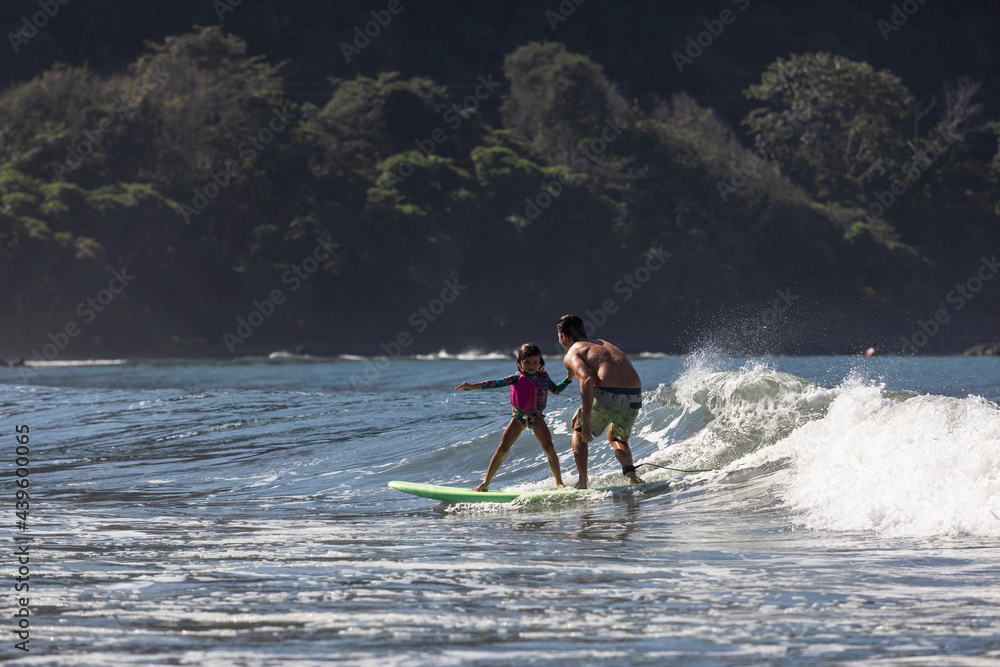 Young 5 year old girl rides wave with father Young 5 year old girl rides wave with father