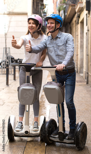 young couple guy and girl walking on segway in streets of european city