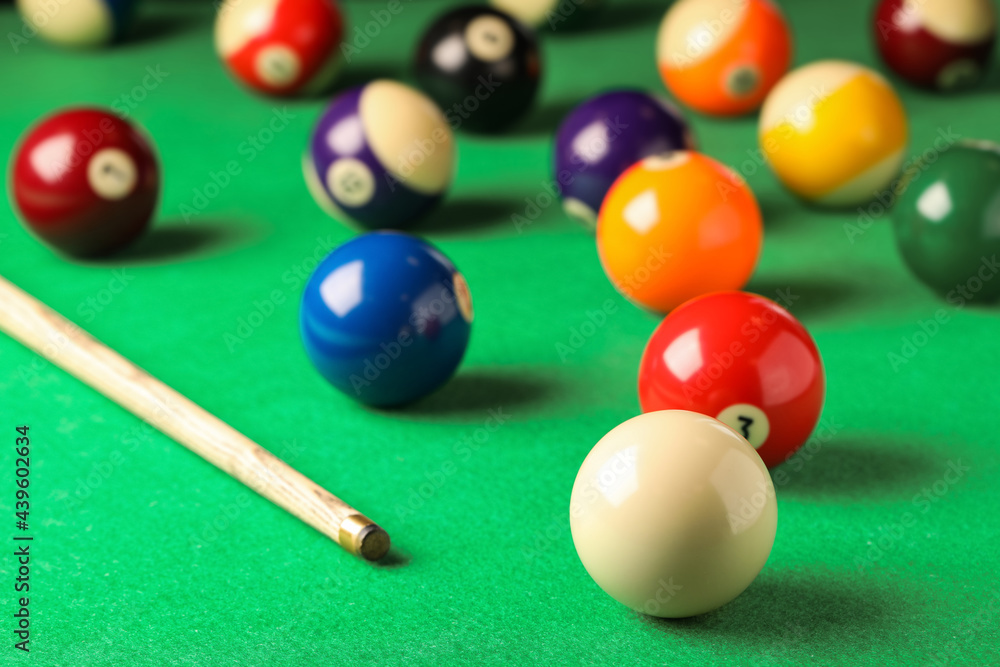 Many colorful billiard balls and cue on green table Many colorful billiard balls and cue on green table