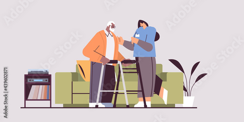 nurse or volunteer supporting elderly man with walkers home care services healthcare and social support