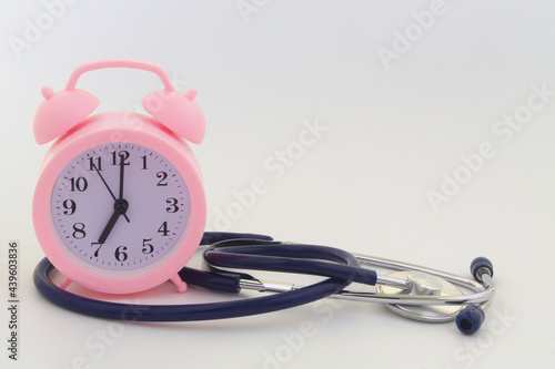 Stethoscope and alarm clock on gray background, copy space. Time to check health and medical insurance concept.