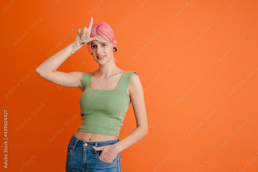 Young white woman with pink hair pointing finger upward Young white woman with pink hair pointing finger upward