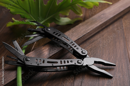 Modern compact portable multitool on wooden table photo