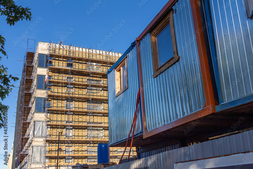 Construction trailer against the background of an apartment building under construction Construction trailer against the background of an apartment building under construction