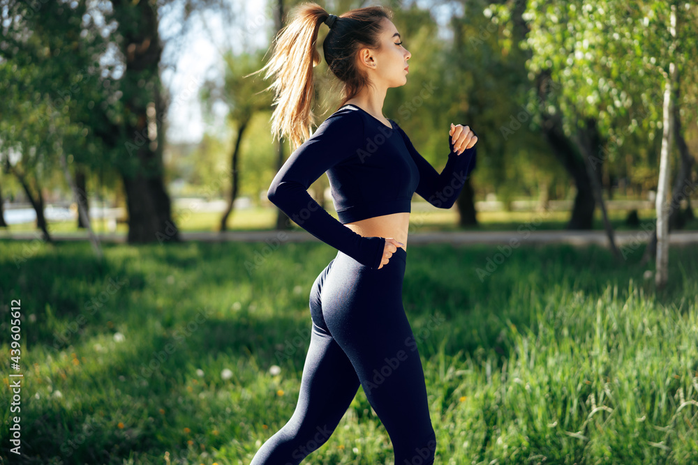Athletic fit young woman jogging early in the morning in park Athletic fit young woman jogging early in the morning in park