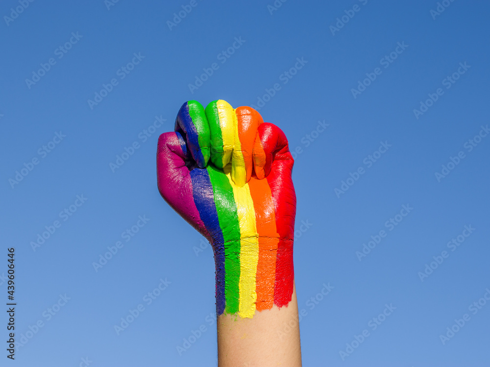 Photo of a raised fist colored with the rainbow color for lgbtq community. - obrazy, fototapety, plakaty 