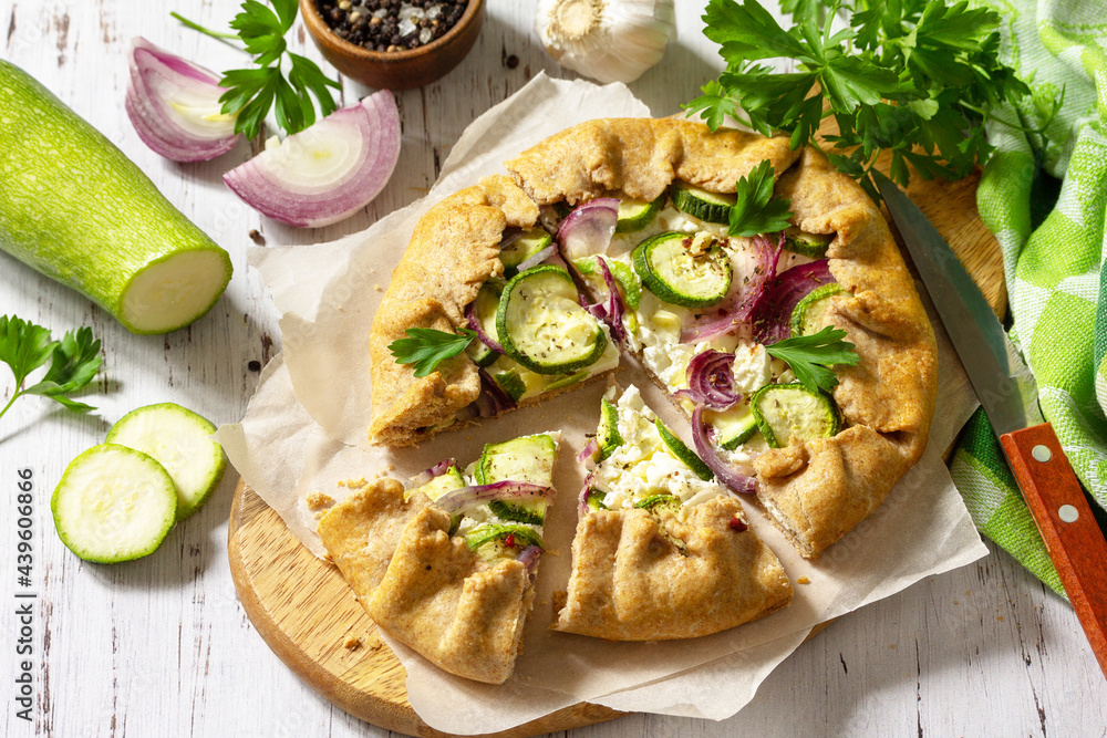 Healthy rye flour baked goods, gluten free, diet food. Galette with zucchini, onions and feta cheese on a wooden table.