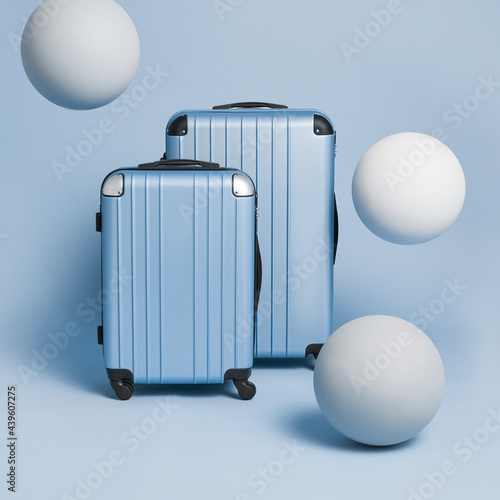 2 blue suitcases on a blue bagkgrounds with big white balls flying around