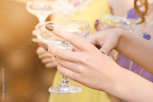 Hand of a girl with a glass of champagne at a party