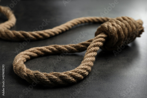 Rope noose with knot on grey table, closeup