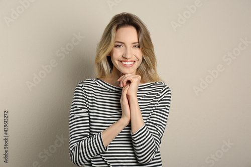 Portrait of happy young woman with beautiful blonde hair and charming smile on beige background © New Africa