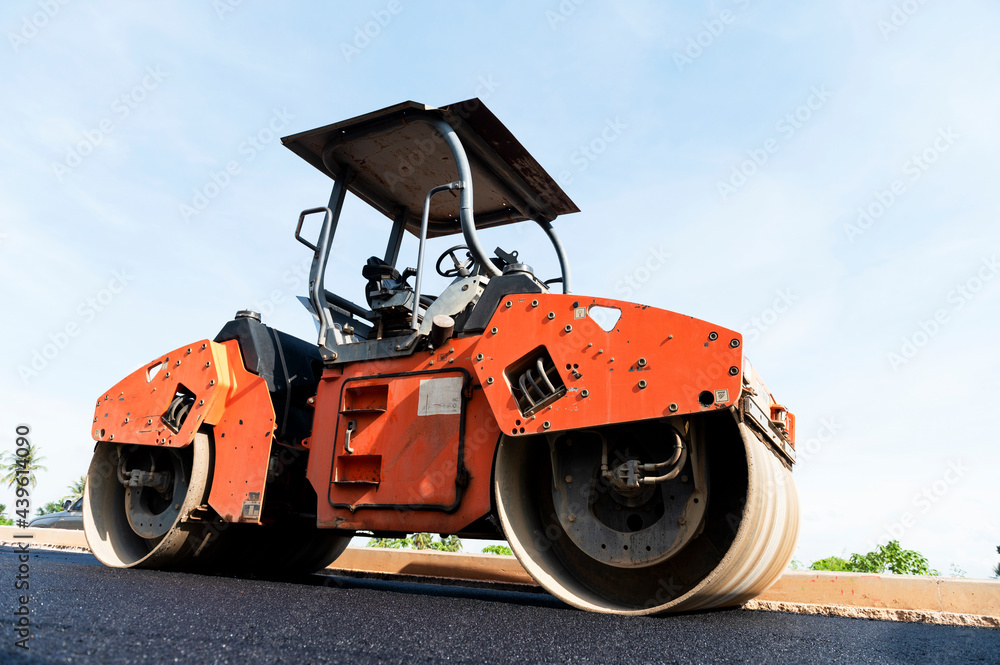 Asphalt road roller with heavy vibration roller compactor press new hot asphalt on the roadway on a road construction site. Heavy Vibration roller at asphalt pavement working. Repairing. Asphalt road roller with heavy vibration roller compactor press new hot asphalt on the roadway on a road construction site. Heavy Vibration roller at asphalt pavement working. Repairing.