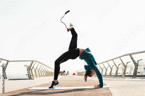 Young sportswoman with prosthesis doing exercise while working out