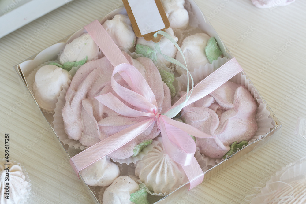 Marshmallow in a gift box. Zephyr in different shapes, classic and in the form of flowers. Lies on a white surface.