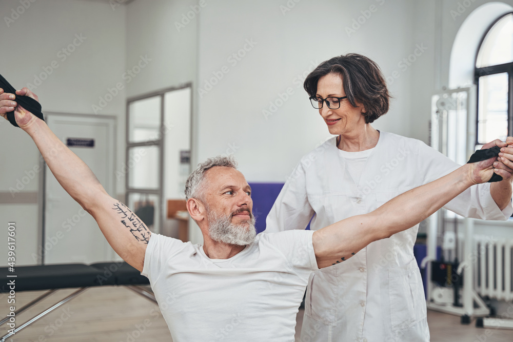 Obraz premium Sportsman working out supervised by a physiotherapist