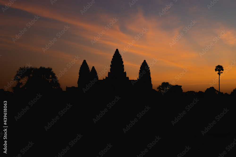 Dawn slowly rises over Angkor Wat, as the orange light reveals the silhouette of the main temple, not far from Siem Reap, Cambodia