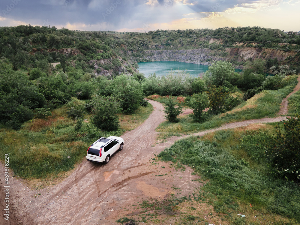 top view of suv car on path road to mine flooded lake top view of suv car on path road to mine flooded lake