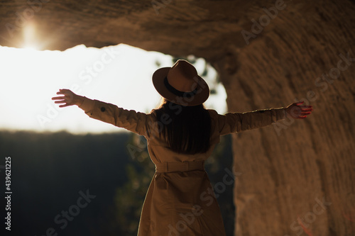 Rear view of a cheerful young woman with raised arms. Freedom and travel concept.