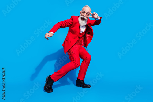 Full length photo of senior man happy positive smile show peace cool v-sign dance party isolated over blue color background
