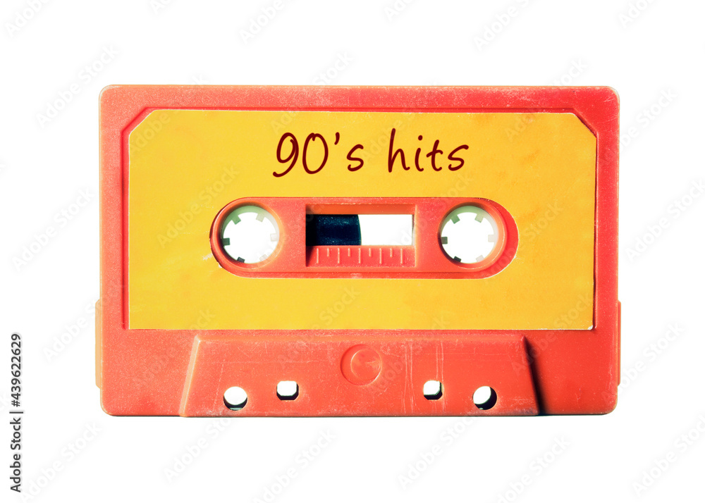 An old vintage cassette tape (obsolete music technology) with the handwritten text: 90's hits. Light red plastic body, vivid orange label, isolated on white.
