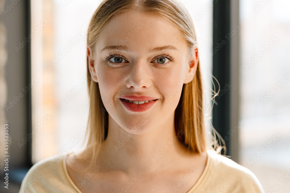 Young blonde white woman smiling and looking at camera indoors Young blonde white woman smiling and looking at camera indoors